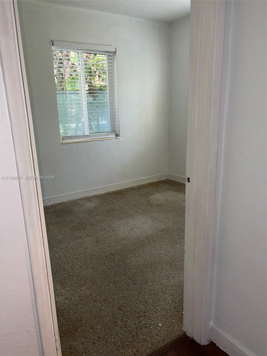 Interior space featuring neutral wall paint, terrazzo flooring, and a single-hung window with horizontal blinds