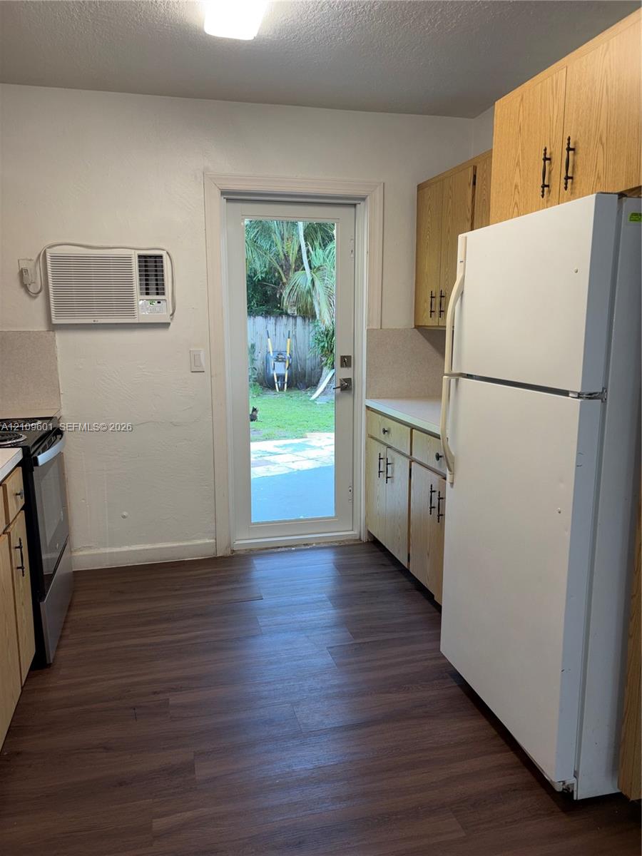 Kitchen featuring wood-finish flooring, light-toned cabinetry with dark hardware, a full-size refrigerator, electric range, and a glass-paneled exterior door