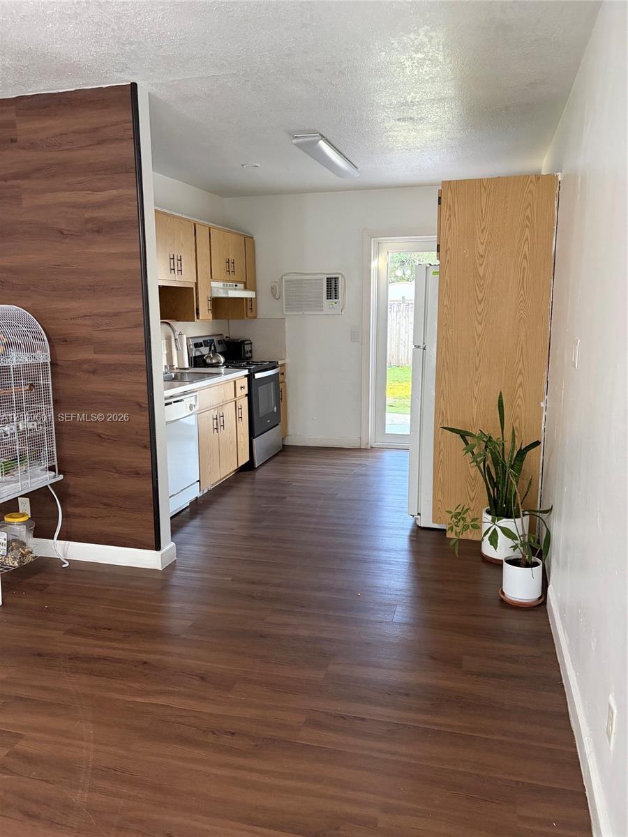 Kitchen featuring wood-finish flooring, wood cabinetry, stainless steel appliances, and a glass-paneled exterior door