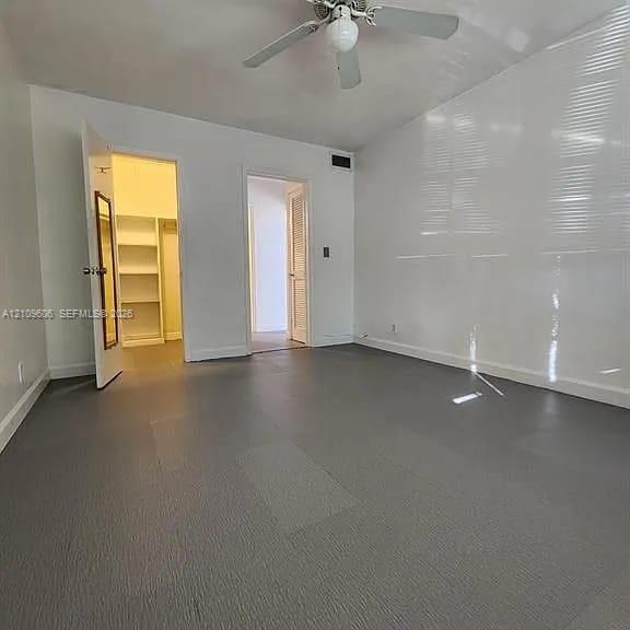 Room featuring gray resilient flooring, built-in shelving, and a ceiling fan with light fixture