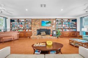 Exposed brick masonry fireplace with a raised hearth, floor-to-ceiling custom built-in wooden cabinetry, and wood-finish flooring
