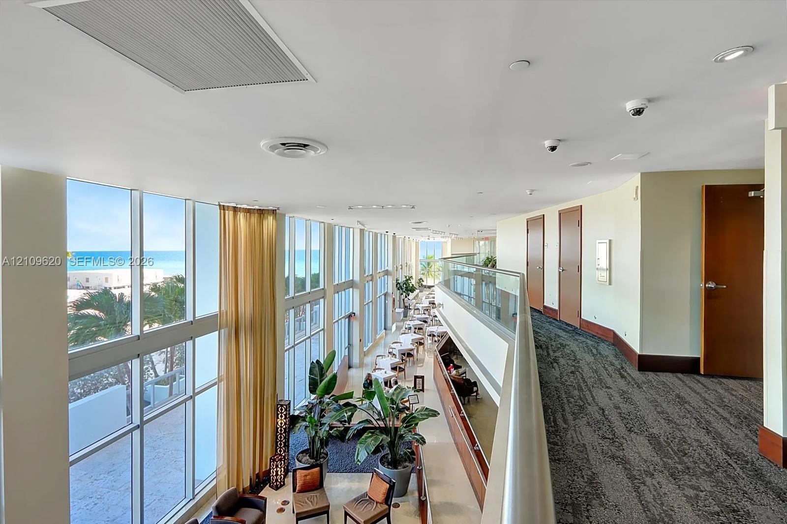 Floor-to-ceiling windows, glass paneled balcony railing, high ceilings, recessed lighting, and carpeted flooring
