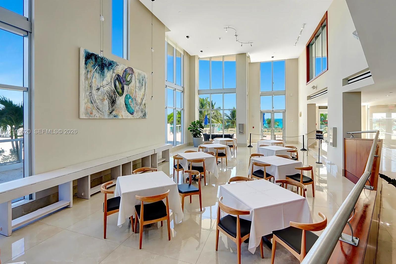Expansive common area featuring floor-to-ceiling windows, soaring vaulted ceilings, polished tile flooring, and custom built-in bench seating
