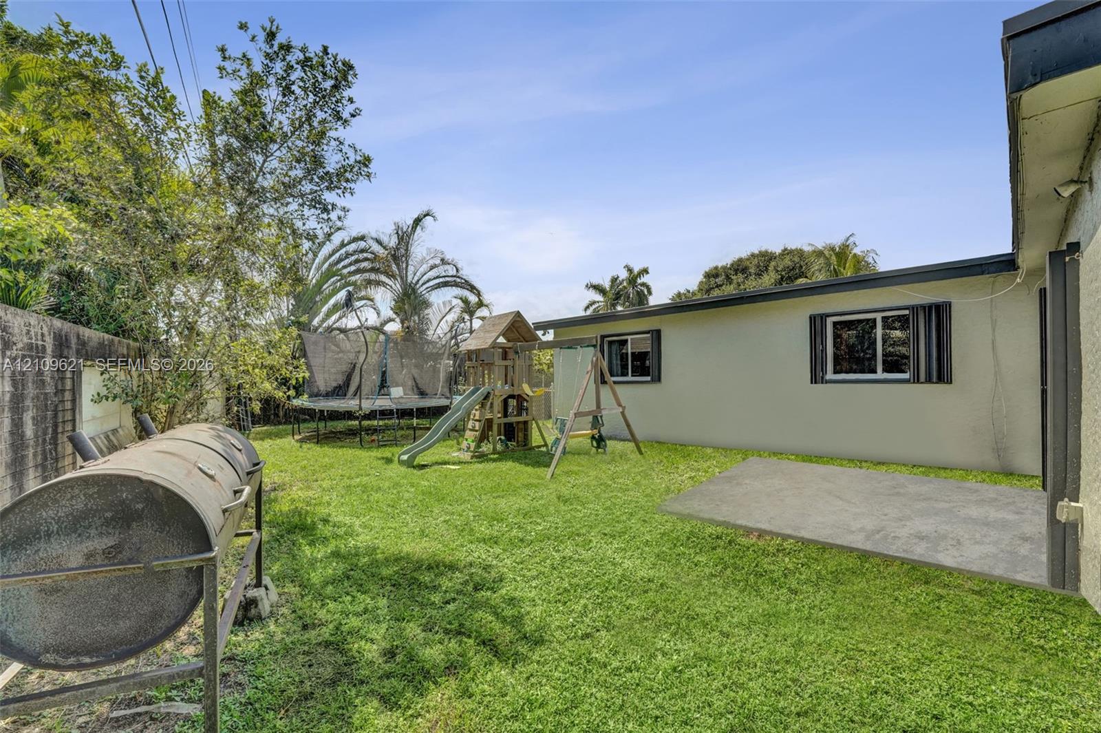 Fenced backyard featuring a manicured lawn, concrete patio, and masonry perimeter wall