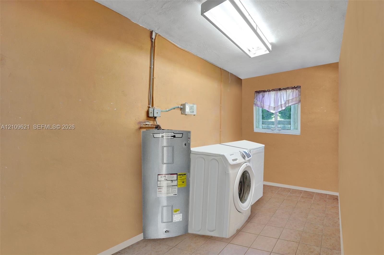 Utility space featuring ceramic tile flooring, a mounted electric water heater, and a rectangular window