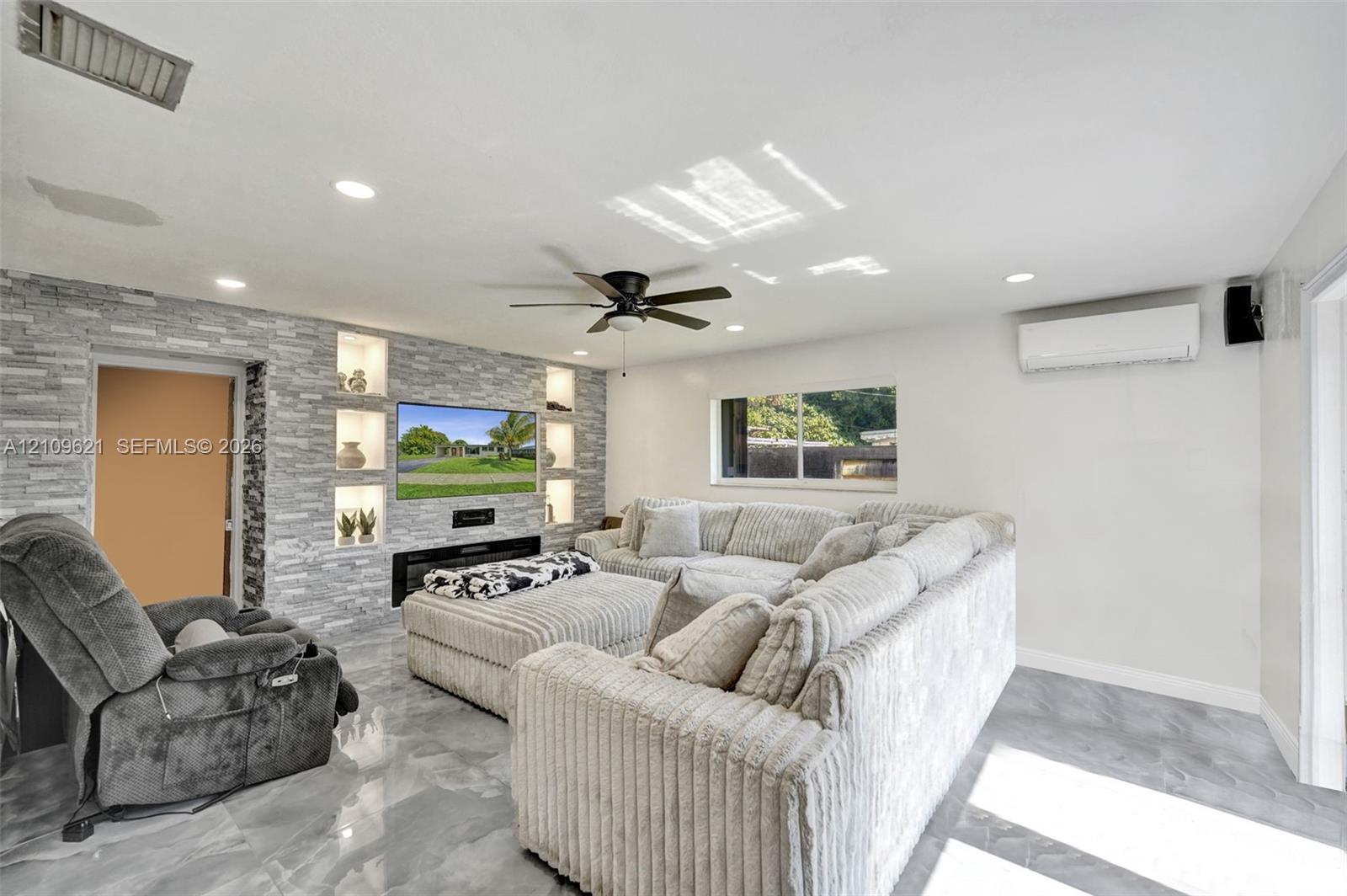 Stacked stone accent wall with integrated shelving, built-in electric fireplace, recessed lighting, ceiling fan, and tile flooring