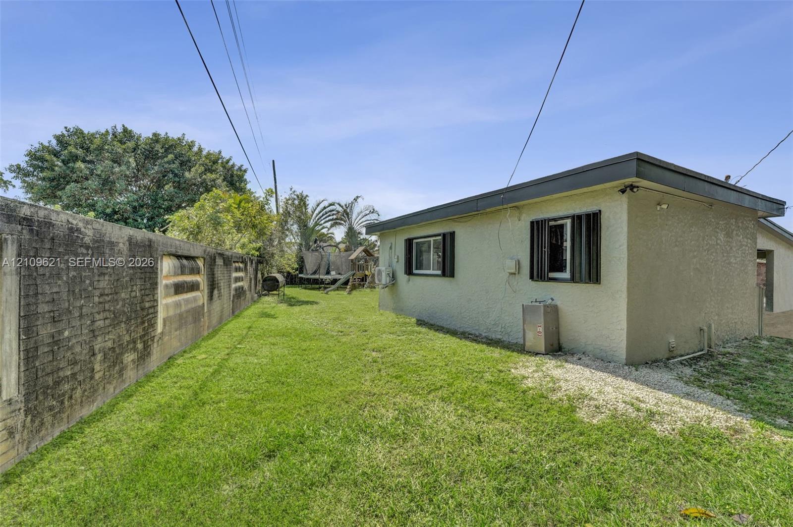 Side yard featuring a stucco exterior, window shutters, and a masonry perimeter wall