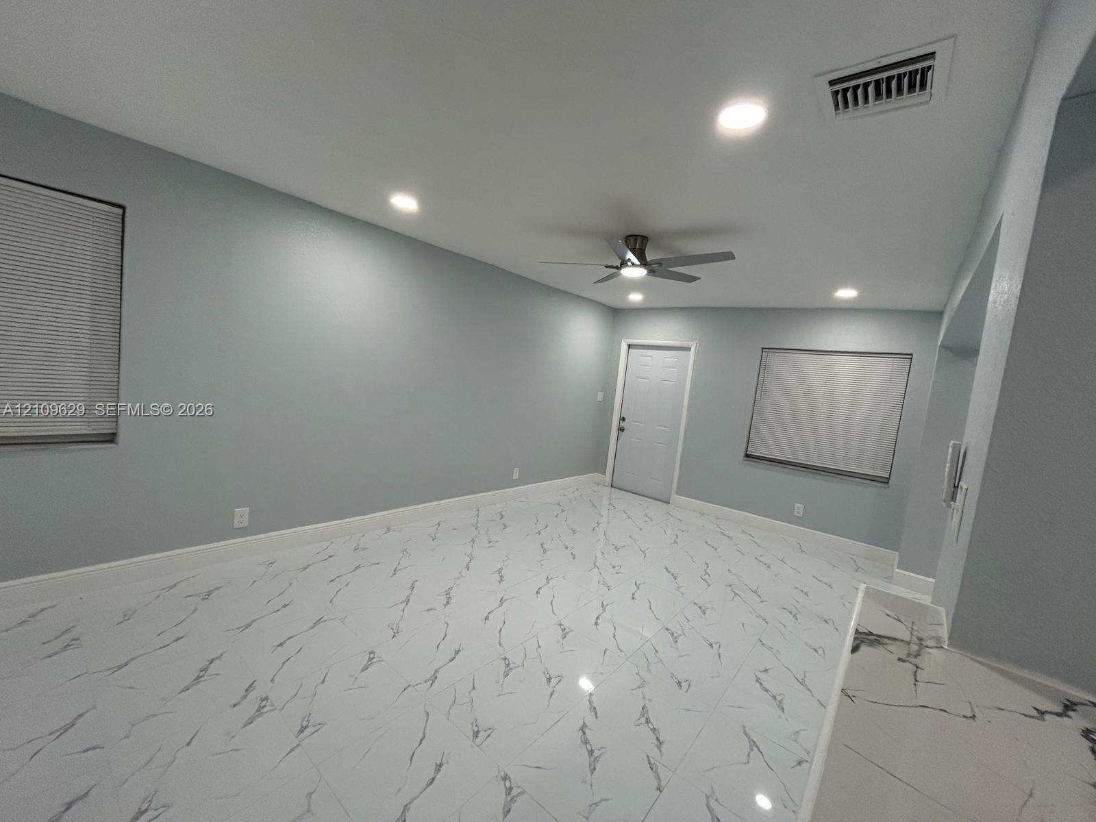 Large-format stone-patterned tile flooring, recessed ceiling lighting, and a multi-speed ceiling fan