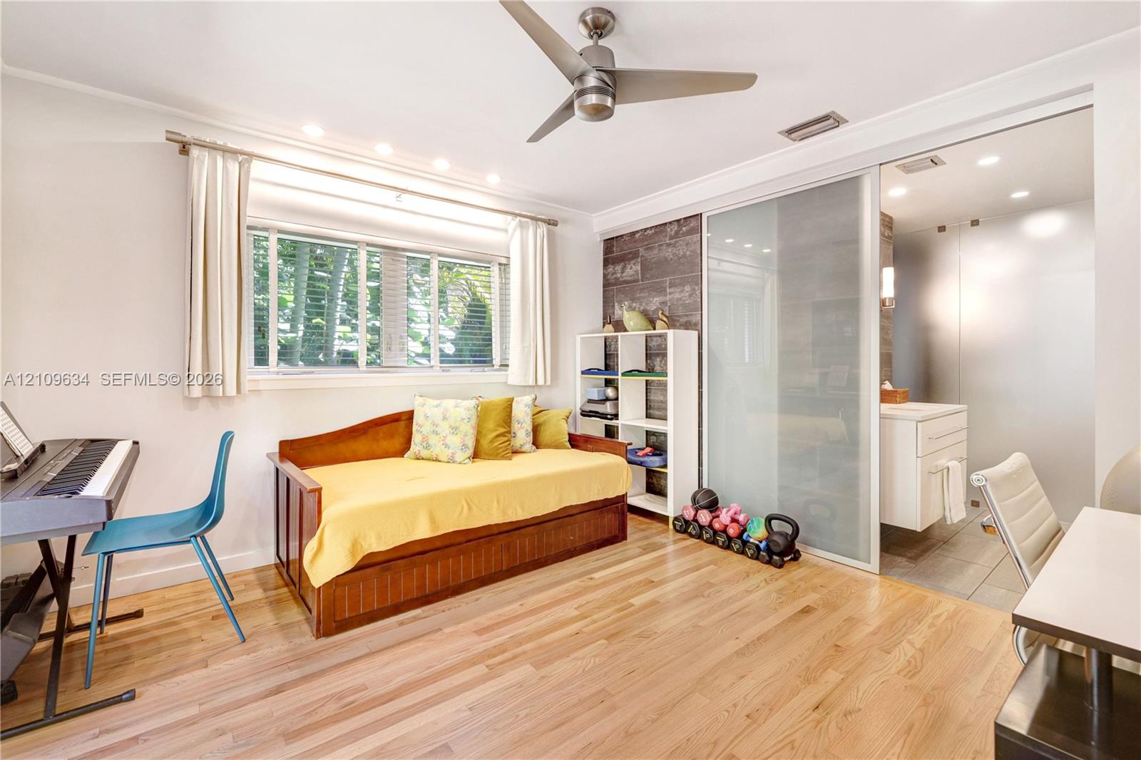 Hardwood flooring, recessed lighting, ceiling fan, decorative wood-finish wall accent, and sliding frosted glass partition