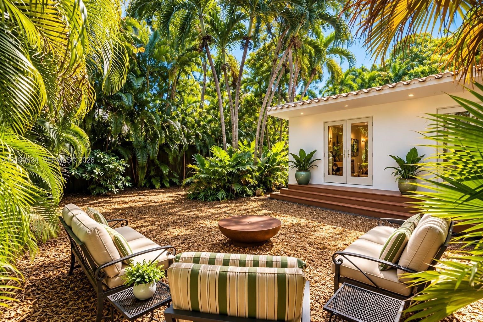 Private backyard featuring a gravel surface, mature palm trees, recessed exterior lighting, a tiled roofline, and elevated wood-finish entry steps