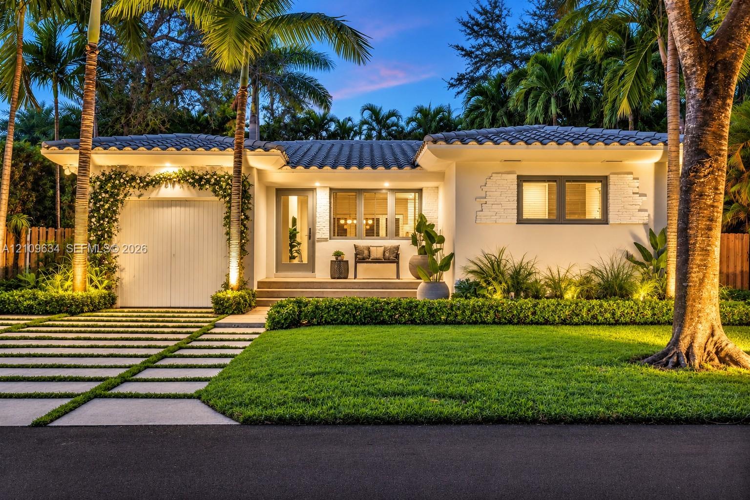 Single-story residence featuring a tile roof, stucco exterior with stone accents, integrated garage, and a paver-style driveway with turf accents