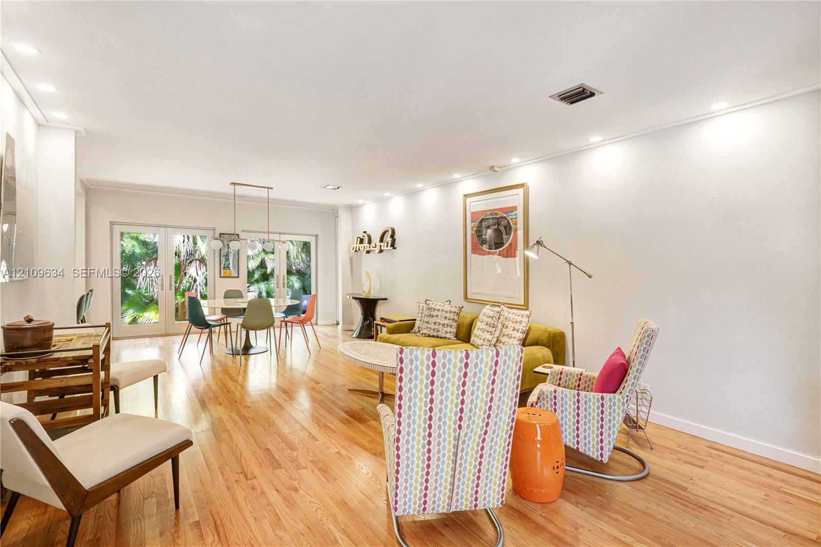 Open-concept living space featuring wood-finish flooring, recessed lighting, and dual glass-paneled double doors providing access to the exterior