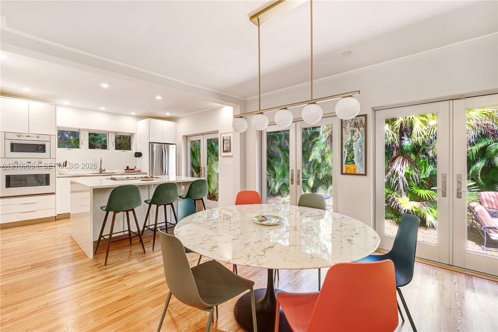 Kitchen featuring white cabinetry, an island with countertop seating, stainless steel appliances, wood-finish flooring, and dual glass-paneled exterior doors