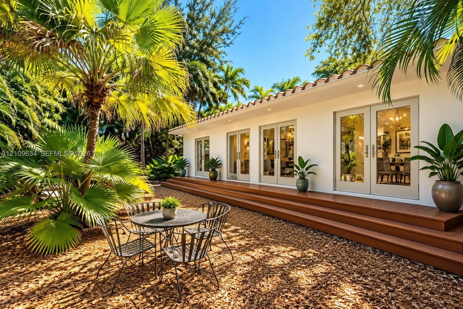 Exterior featuring a multi-tiered composite deck, white stucco siding, mission-style clay tile roofline, and multiple sets of glass-paned French doors