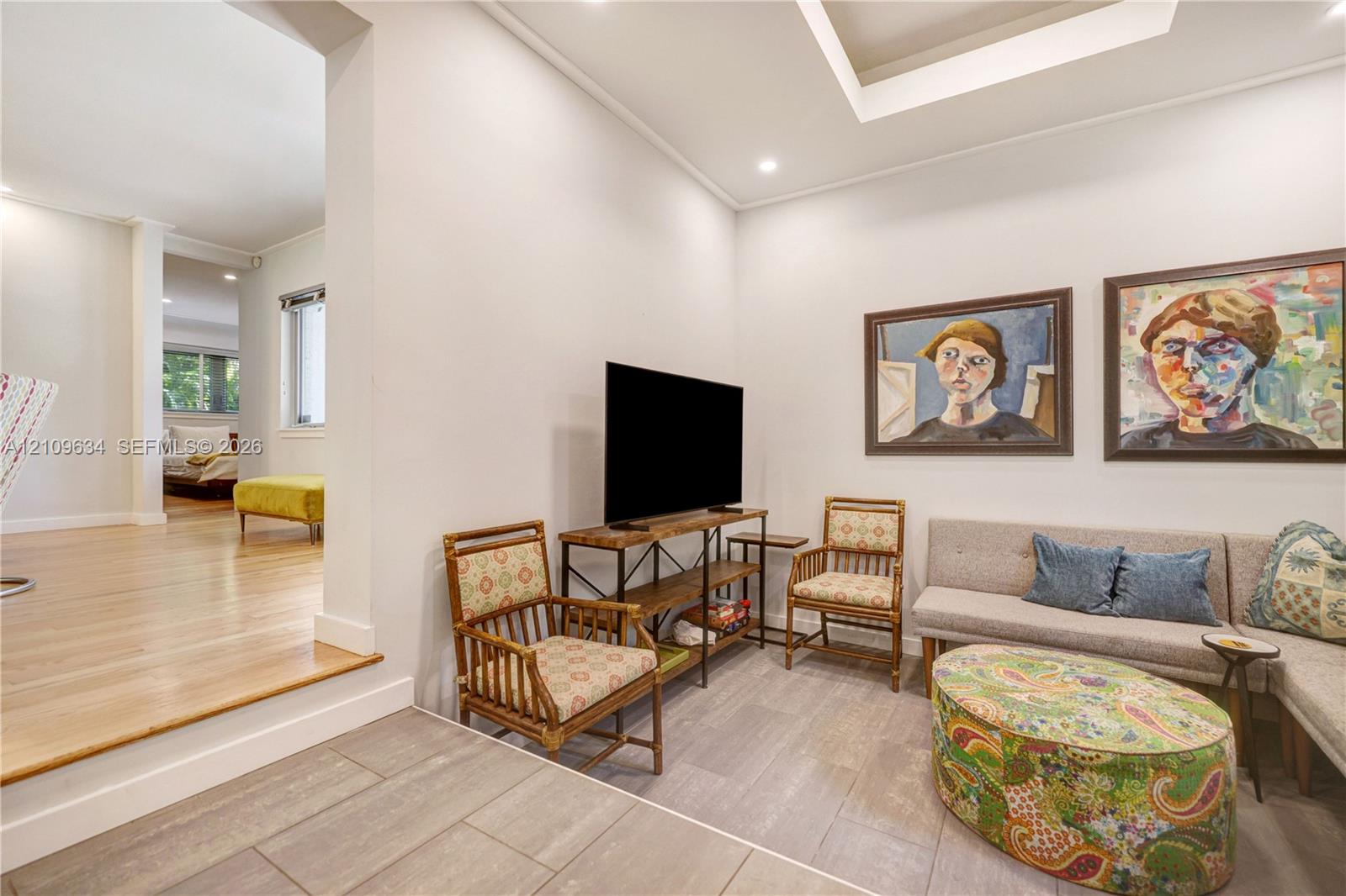 Recessed tray ceiling, light-toned wood-finish flooring, and large-format rectangular floor tile