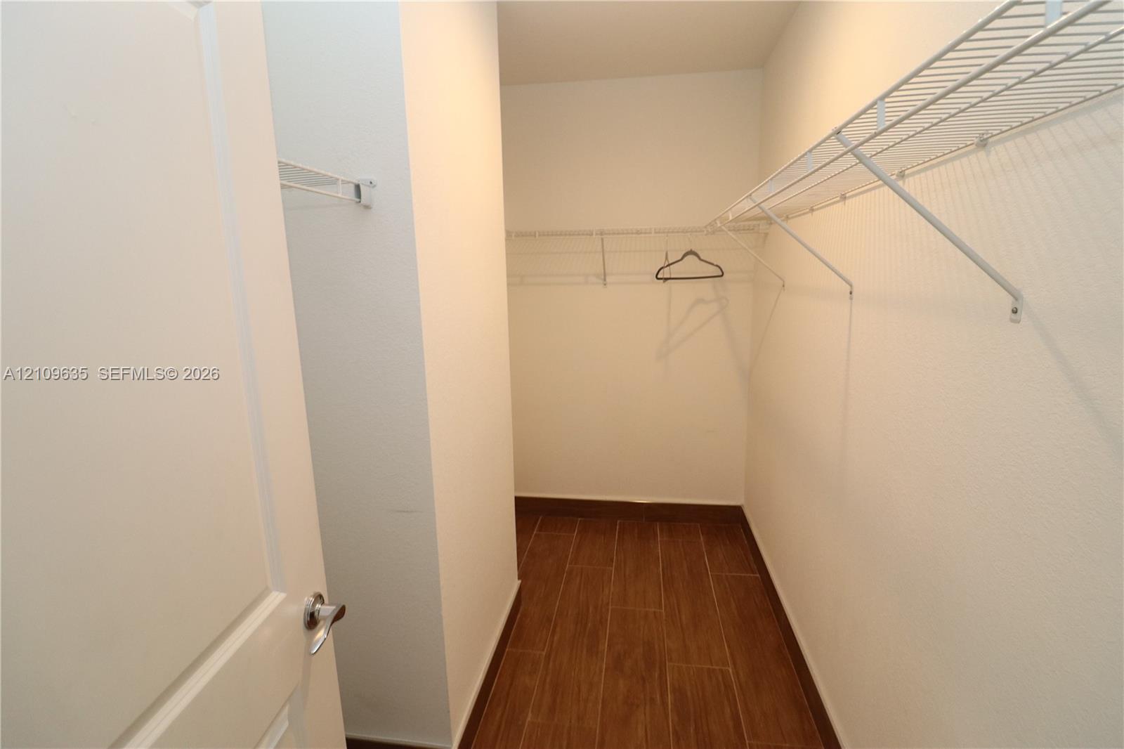 Walk-in closet featuring wood-finish tile flooring and built-in metal shelving