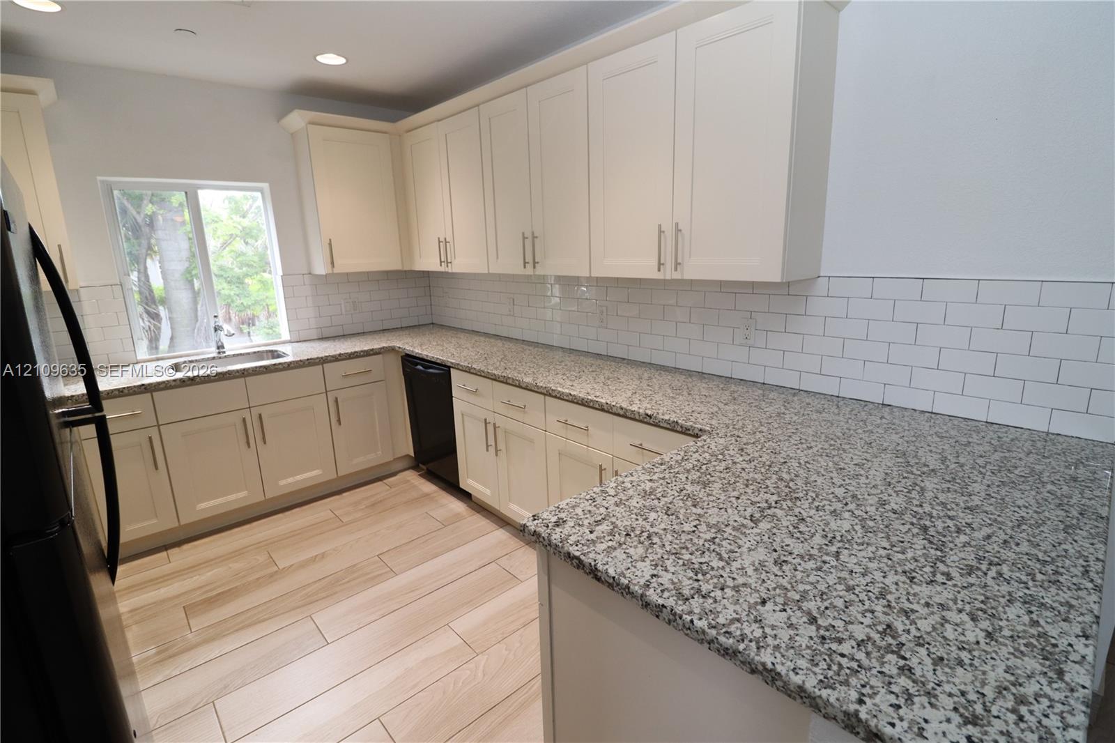 Kitchen featuring light-toned cabinetry, stone-finish countertops, subway tile backsplash, wood-finish flooring, and recessed ceiling lighting