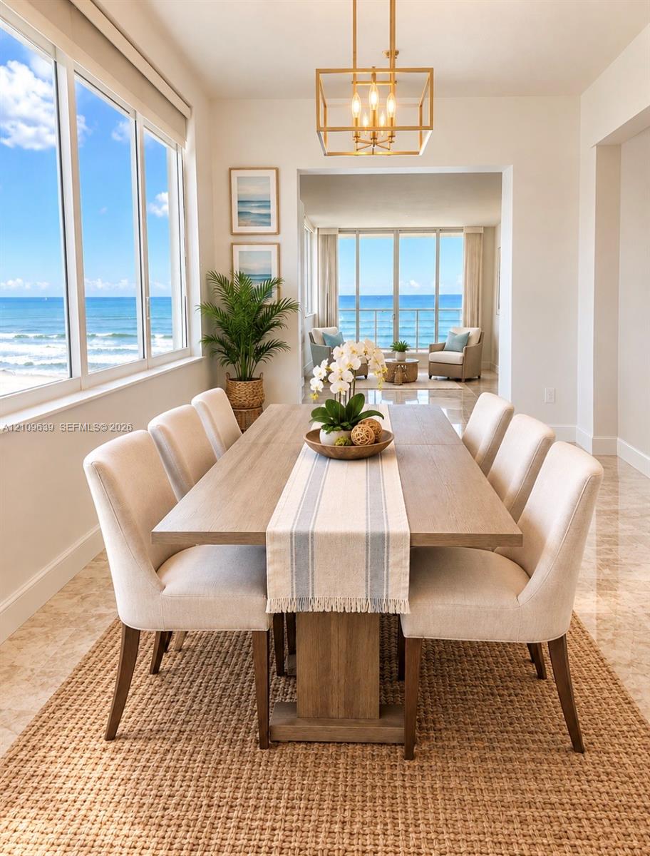 Floor-to-ceiling windows, polished stone flooring, gold-tone geometric chandelier, and direct oceanfront exposure