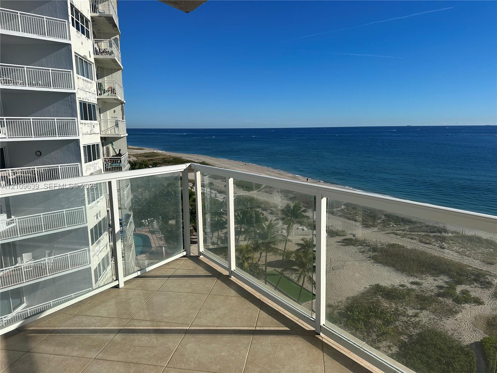Private balcony featuring tile flooring and a glass-paneled railing overlooking the coastline