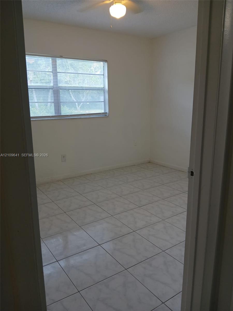Room featuring neutral-toned ceramic tile flooring, horizontal window blinds, and a central ceiling fan with an integrated light fixture
