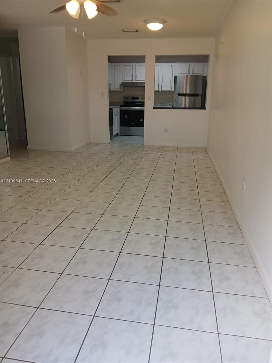 Ceramic tile flooring, white cabinetry, and stainless steel kitchen appliances, including a range and refrigerator Ceramic tile flooring, white cabinetry, and stainless steel kitchen appliances, including a range and refrigerator