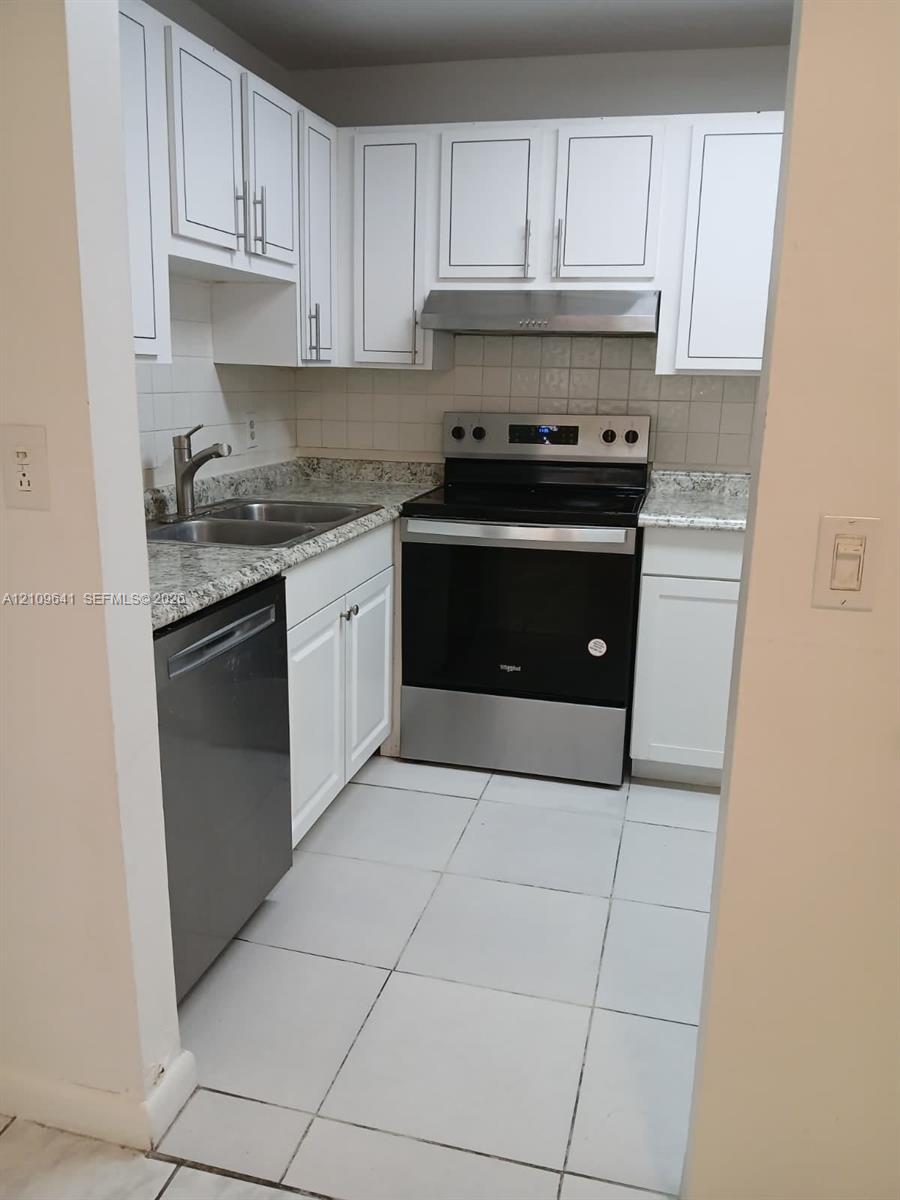 Kitchen featuring white cabinetry, stone-finish countertops, stainless steel appliances, a double-basin sink, and tile flooring Kitchen featuring white cabinetry, stone-finish countertops, stainless steel appliances, a double-basin sink, and tile flooring
