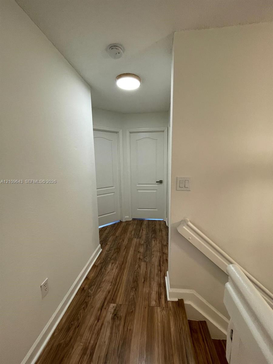 Wood-finish flooring, white paneled interior doors, and a neutral color palette featuring a ceiling-mounted light fixture