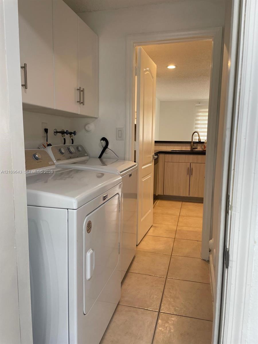Laundry area featuring white built-in cabinetry, tile flooring, and a recessed ceiling light