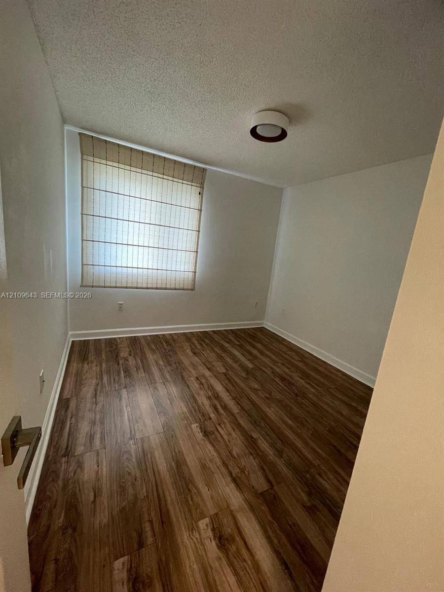 Interior room featuring wood-finish flooring, a neutral color palette, and a flush-mount circular ceiling light fixture