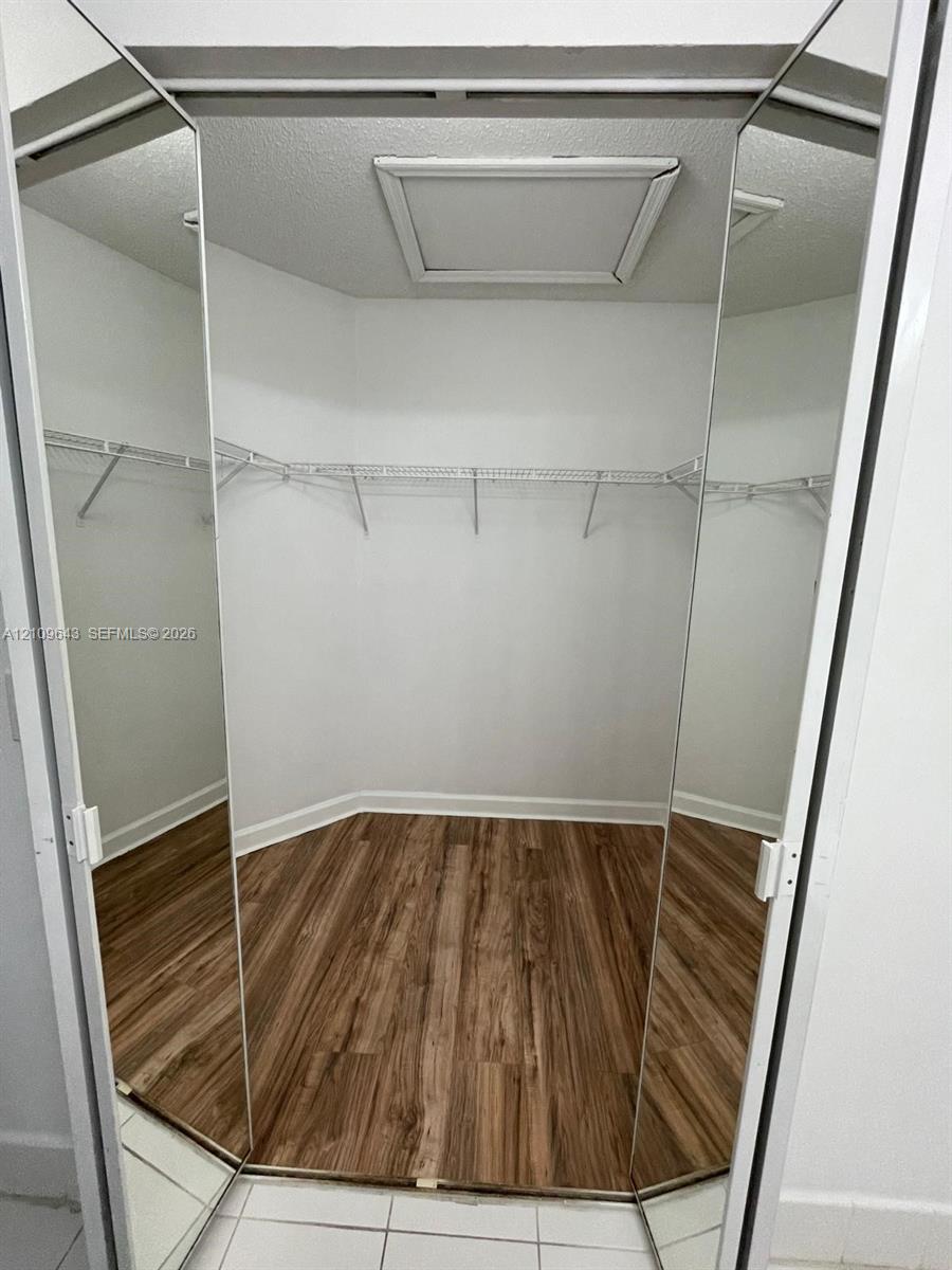 Walk-in closet featuring mirrored bifold doors, wood-finish flooring, and integrated wire shelving