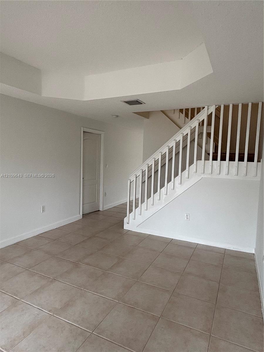 Ceramic tile flooring throughout with a staircase featuring a white wooden balustrade and handrail