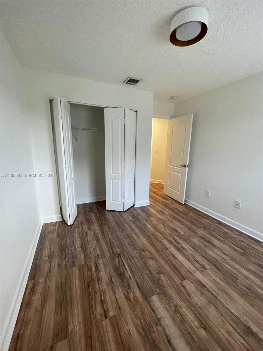 Room featuring wood-finish flooring, white panel doors, bi-fold closet doors, and a circular flush-mount ceiling light fixture