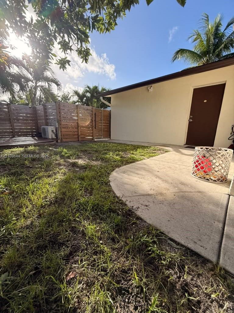 Exterior space featuring a concrete patio, horizontal wood slat privacy fencing, and mature palm trees Exterior space featuring a concrete patio, horizontal wood slat privacy fencing, and mature palm trees