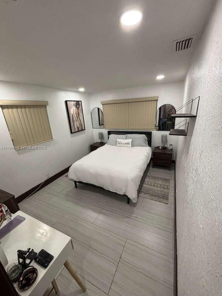 Large-format tile flooring, recessed ceiling lighting, and vertical window blinds Large-format tile flooring, recessed ceiling lighting, and vertical window blinds