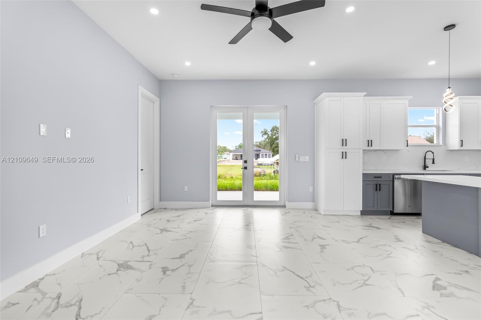 Large-format tile flooring, dual-tone cabinetry, stainless steel appliances, matte black hardware, and double glass-paneled exterior doors