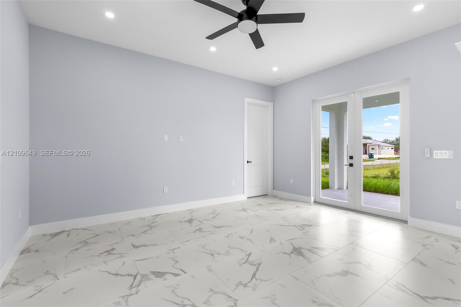 Large-format stone-patterned tile flooring, recessed ceiling lighting, matte black ceiling fan, and full-lite glass French doors