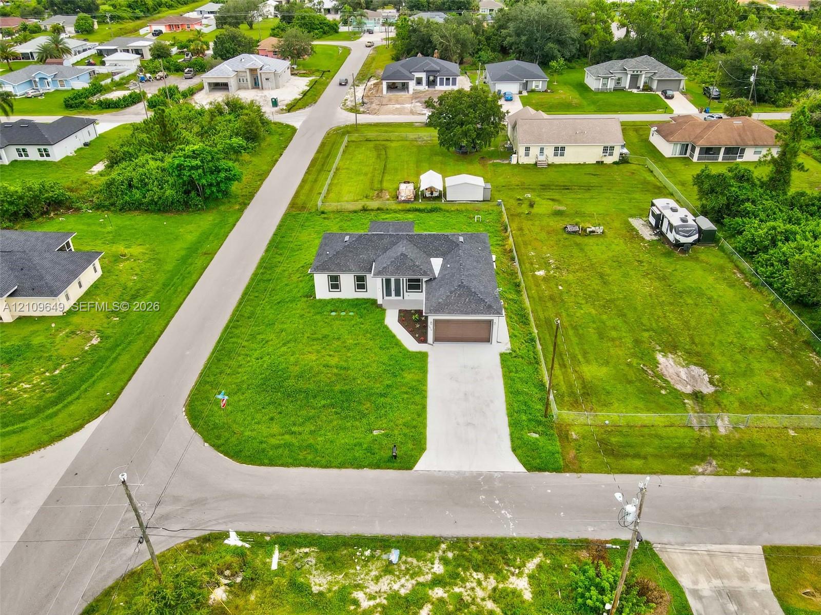 Single-story residence featuring a dark shingled roof, attached two-car garage, concrete driveway, and expansive corner lot