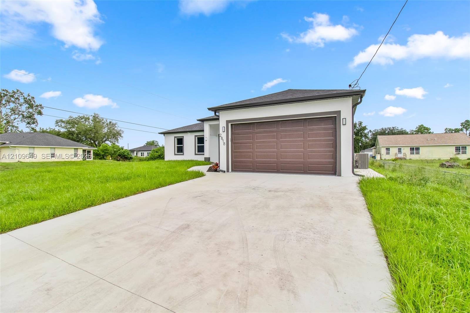 Single-story exterior featuring a stucco facade, concrete driveway, and attached two-car garage with a paneled door