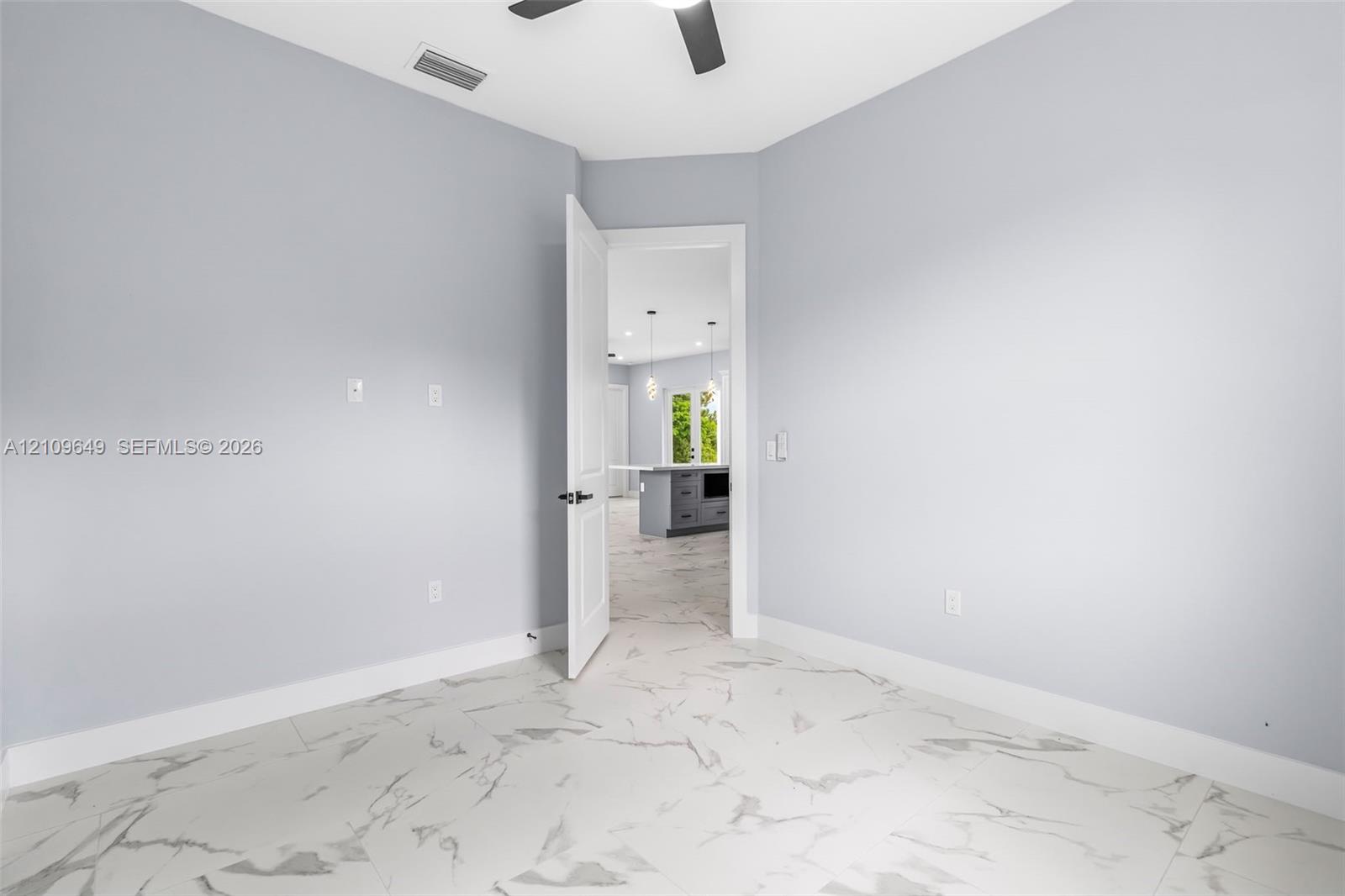 Room featuring large-format tile flooring with a veined pattern, neutral wall paint, and a ceiling-mounted fan