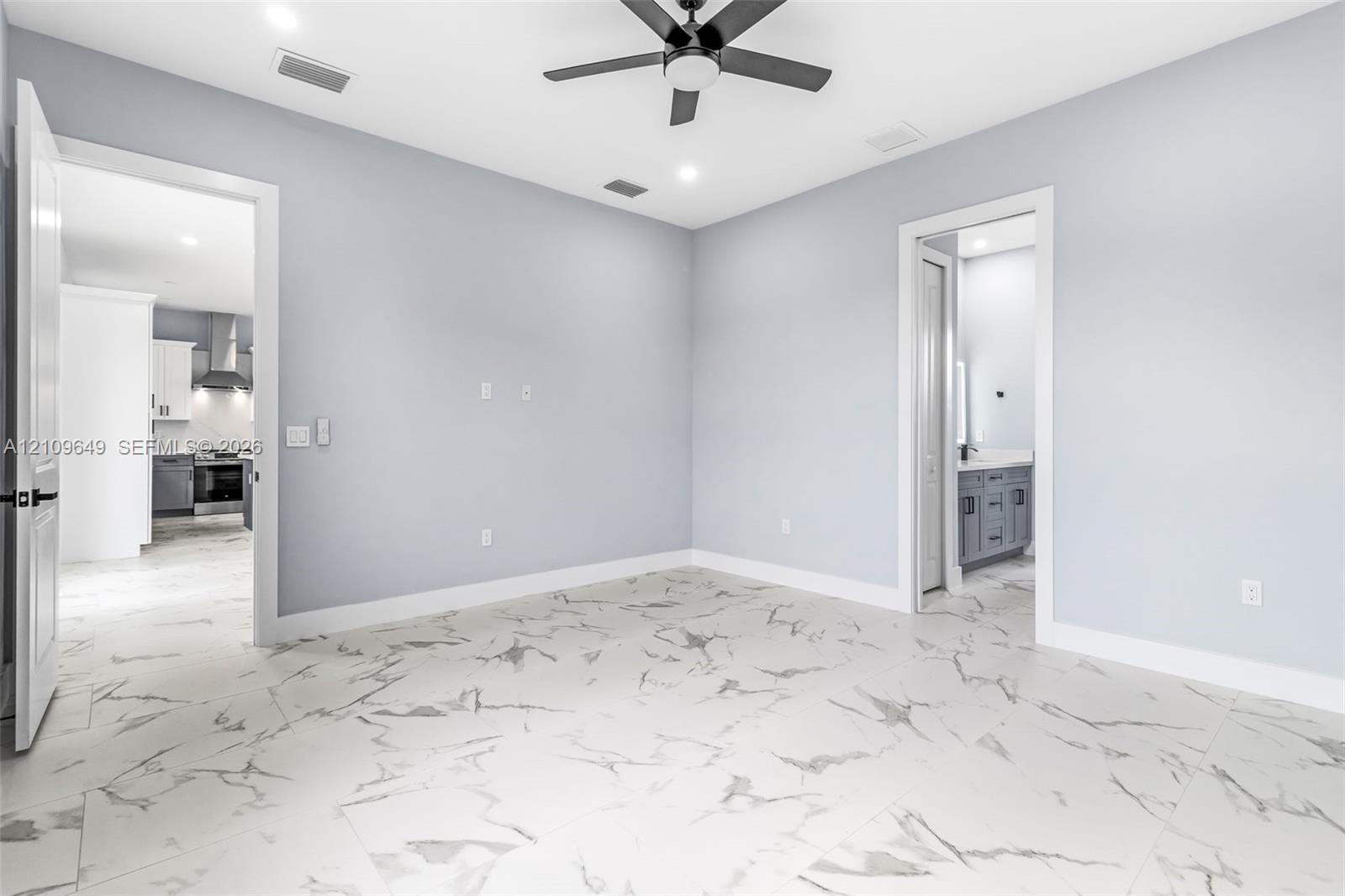 Room featuring large-format tile flooring with a veined pattern, recessed ceiling lighting, and a dark-finish ceiling fan