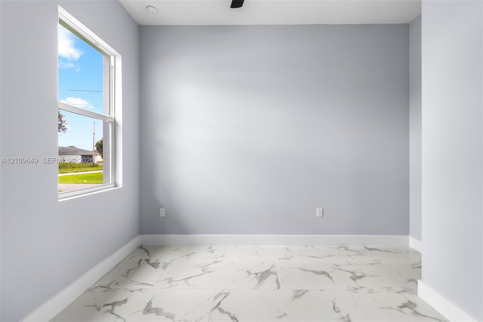 Interior space featuring large-format tile flooring with a marble-finish pattern, light-toned wall paint, and a single-hung window