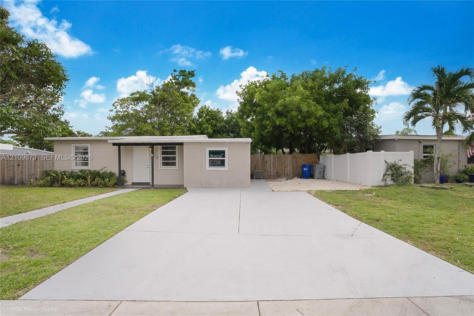 Single-story exterior featuring a concrete driveway, covered front entryway, horizontal sliding windows, and perimeter privacy fencing Single-story exterior featuring a concrete driveway, covered front entryway, horizontal sliding windows, and perimeter privacy fencing