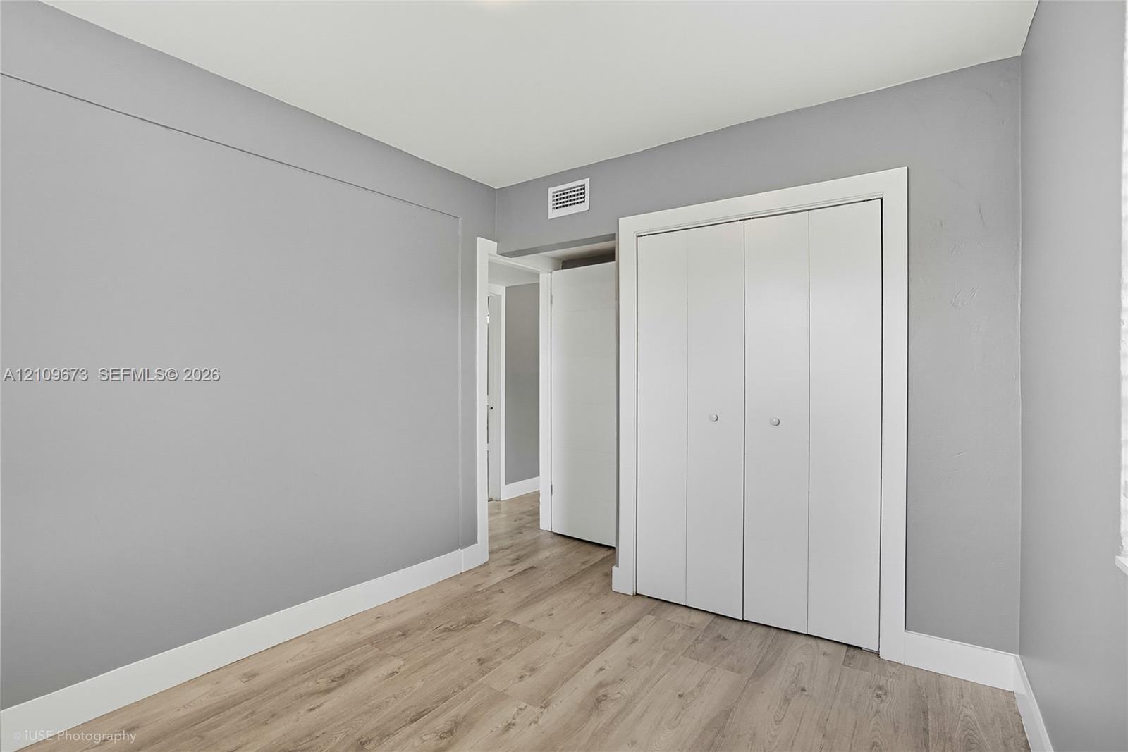 Interior space featuring neutral gray walls, wood-finish flooring, and a white bi-fold closet door
