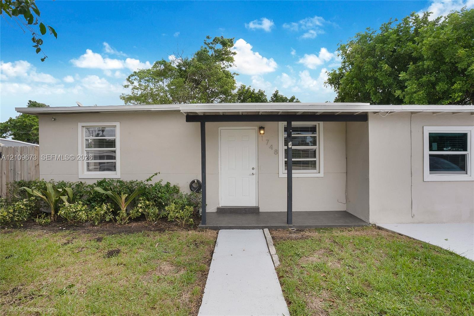 Single-story exterior featuring a neutral-toned facade, covered front entryway, concrete walkway, and landscaped garden beds Single-story exterior featuring a neutral-toned facade, covered front entryway, concrete walkway, and landscaped garden beds