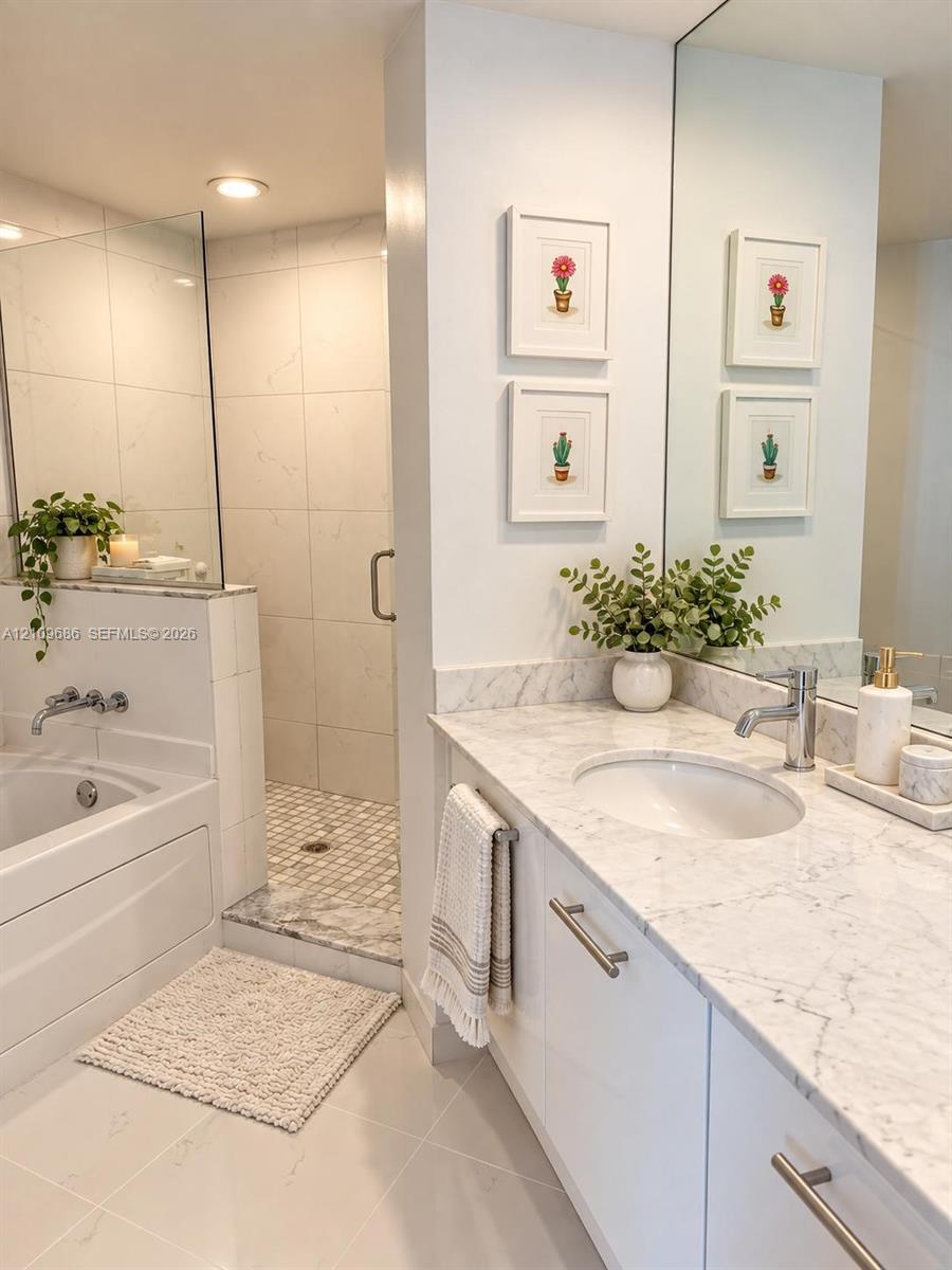 Bathroom featuring a vanity with stone countertop and undermount sink, a recessed soaking tub with wall-mounted faucet, and a separate walk-in shower with glass enclosure and mosaic tile flooring