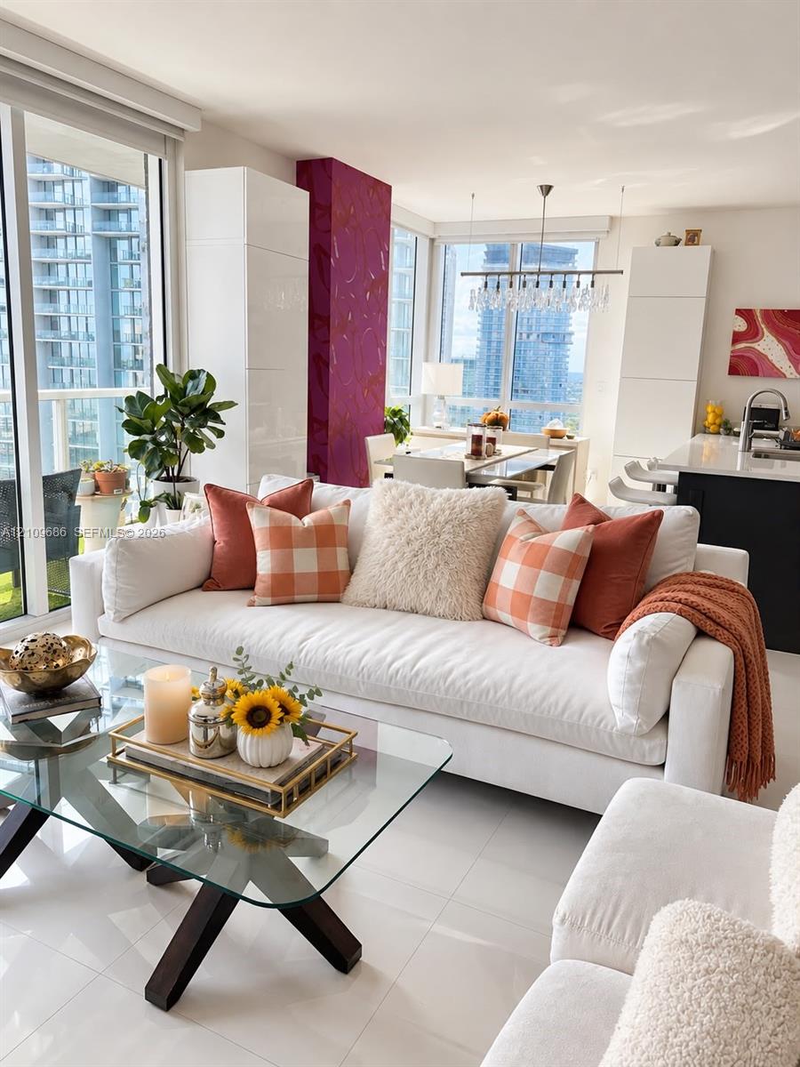 Floor-to-ceiling windows, high-gloss white cabinetry, large-format tile flooring, linear pendant lighting, and a kitchen island with a neutral countertop