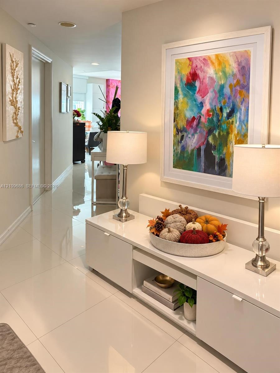 Interior hallway featuring polished tile flooring and a built-in, white high-gloss console with integrated shelving and cabinetry