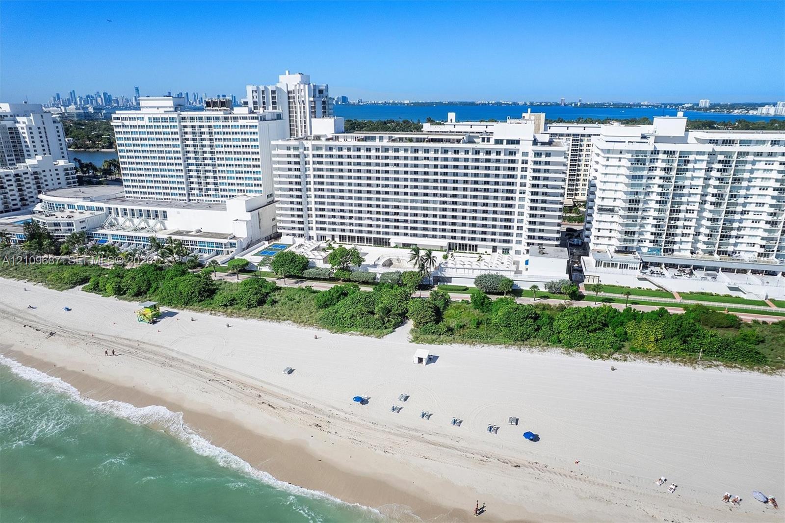Oceanfront high-rise building with direct beach access, coastal landscaping, and exterior balconies