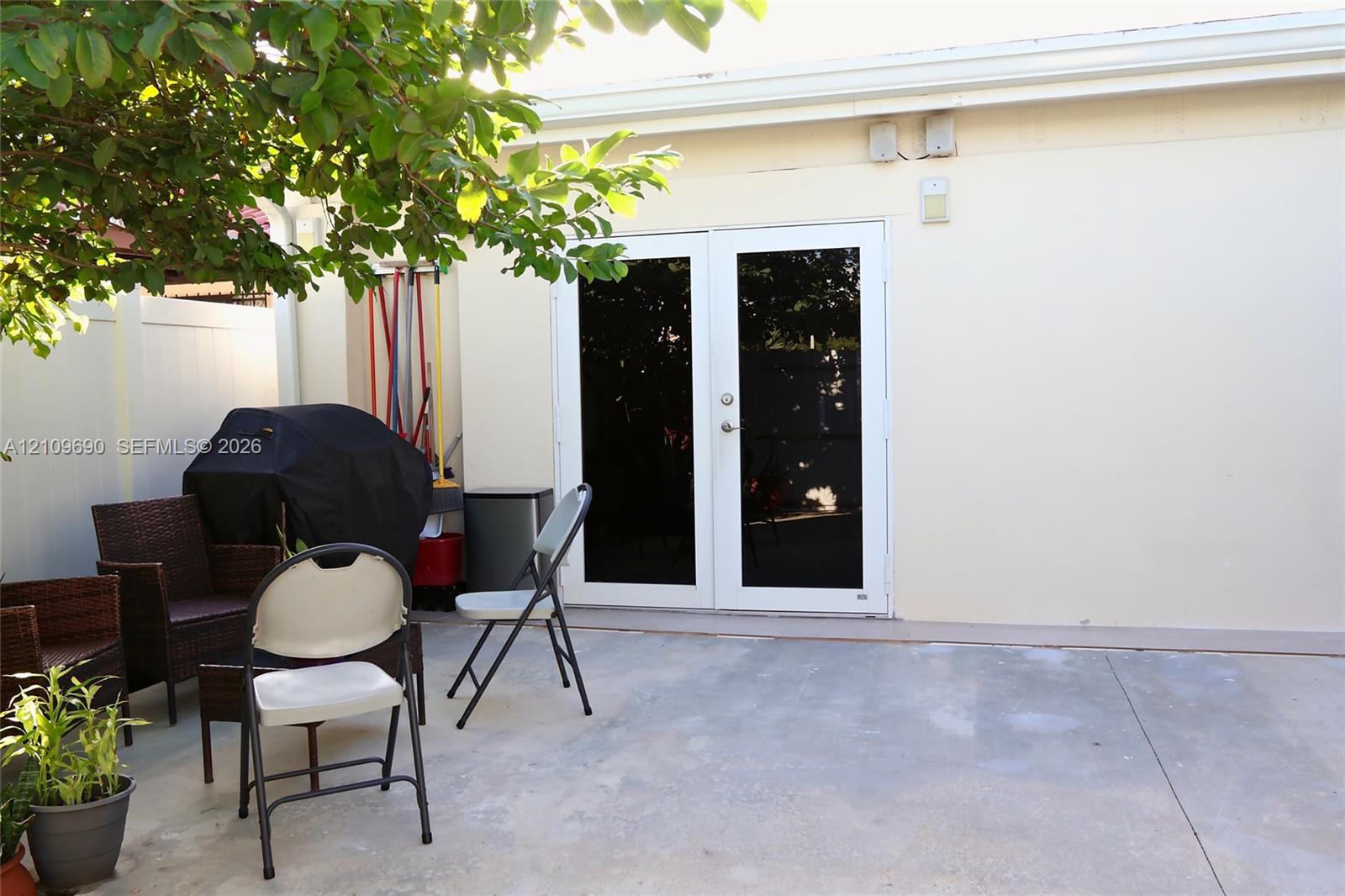 Concrete patio featuring white vinyl perimeter fencing and double glass-paned doors