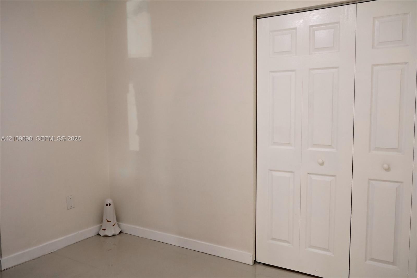 Interior space featuring neutral wall paint and a white bi-fold closet door with recessed panel detailing